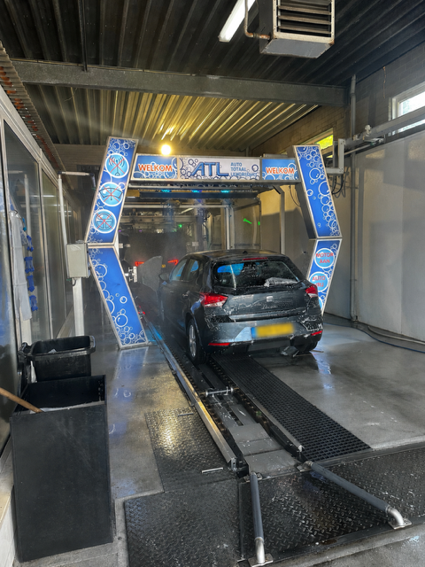Auto wasstraat met wasborstel en waterdamp, klaar voor reiniging.
